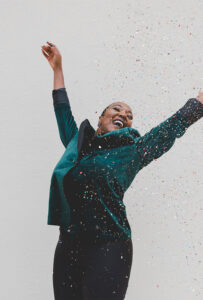 woman raising her hands in joy with confetti raining down.