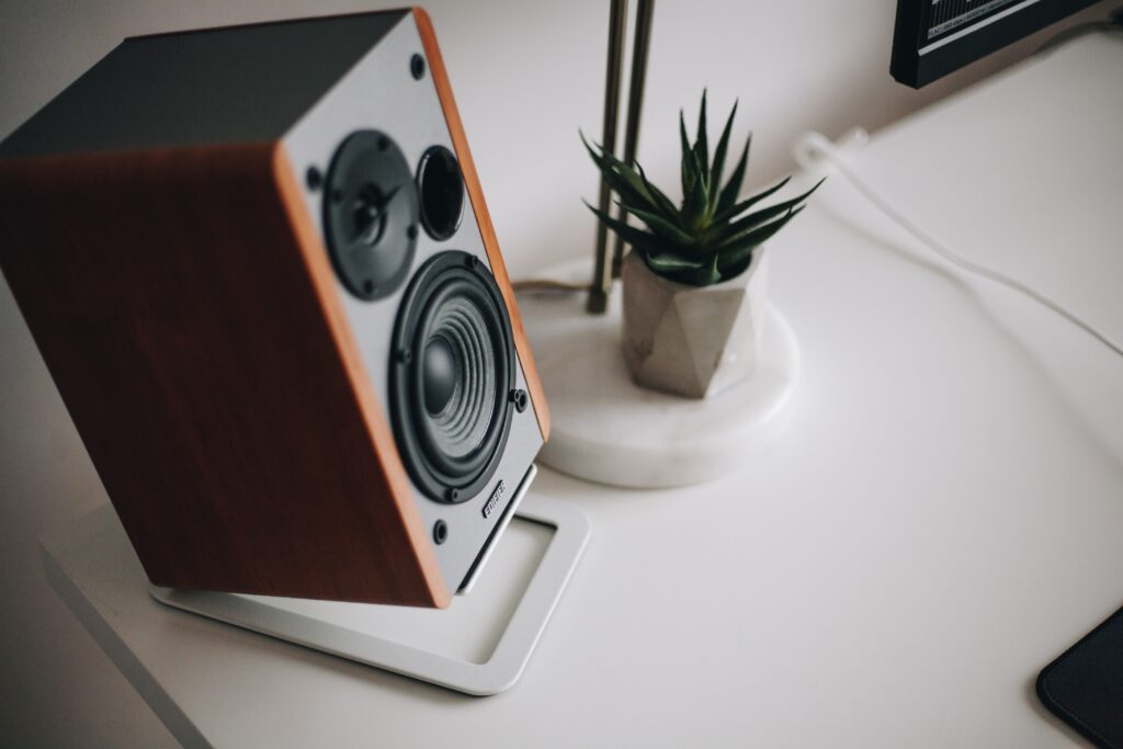 Speaker on a desk next to a succulent playing sound advertising. 