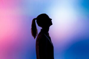 Women silhouetted in front of a purple blue and pink backdrop