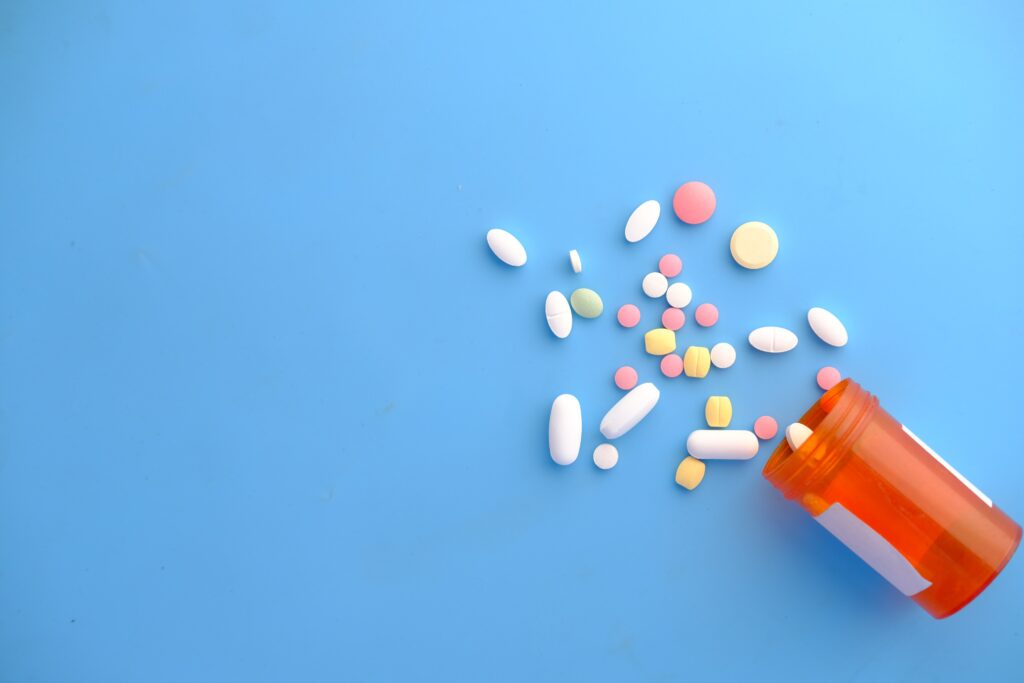 colorful medicine pills spilling out of container