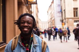 man smiling on street with earbuds in ear